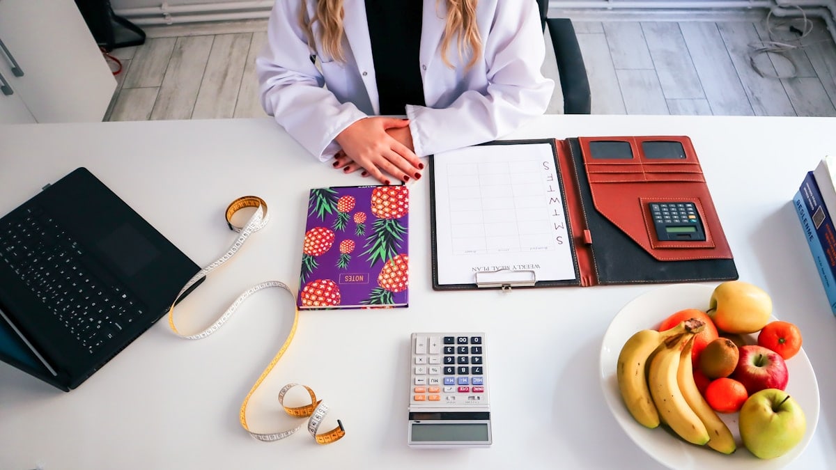a woman sitting at a table with a plate of fruit and a calculator