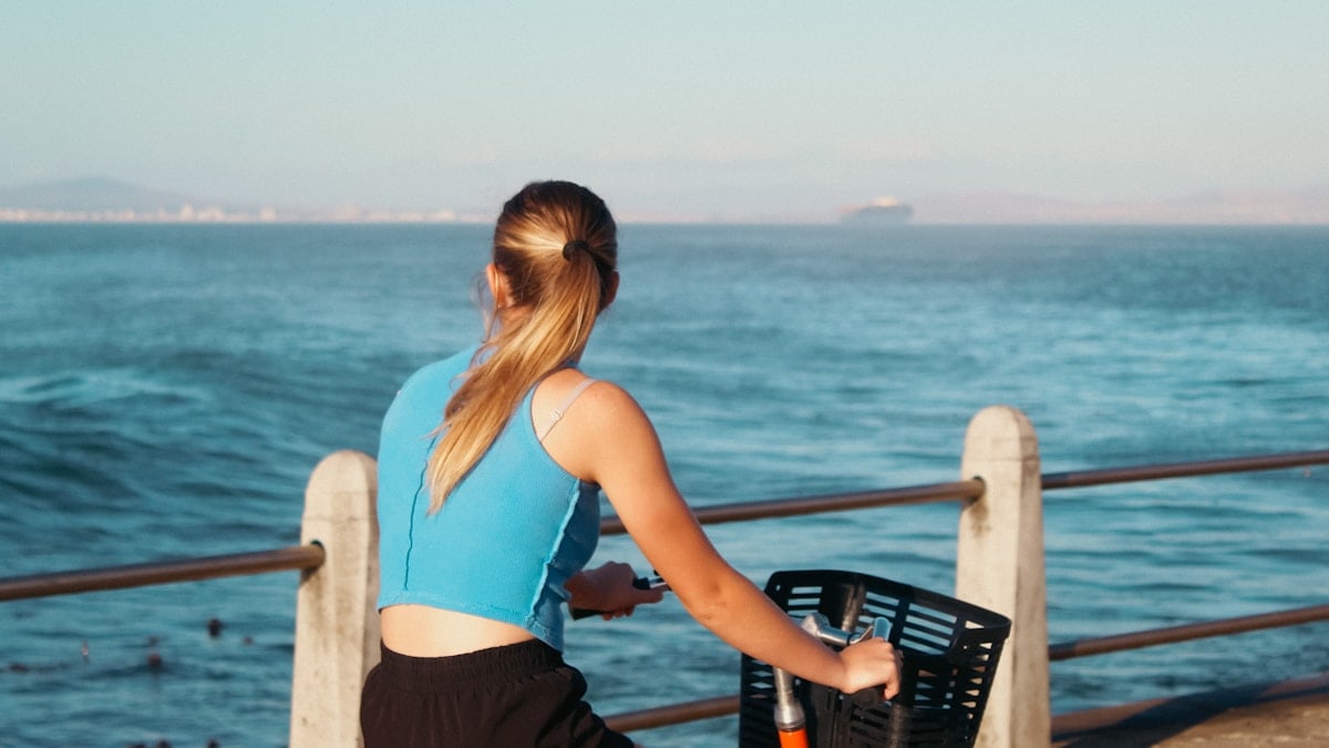 Woman riding a bike by the sea.